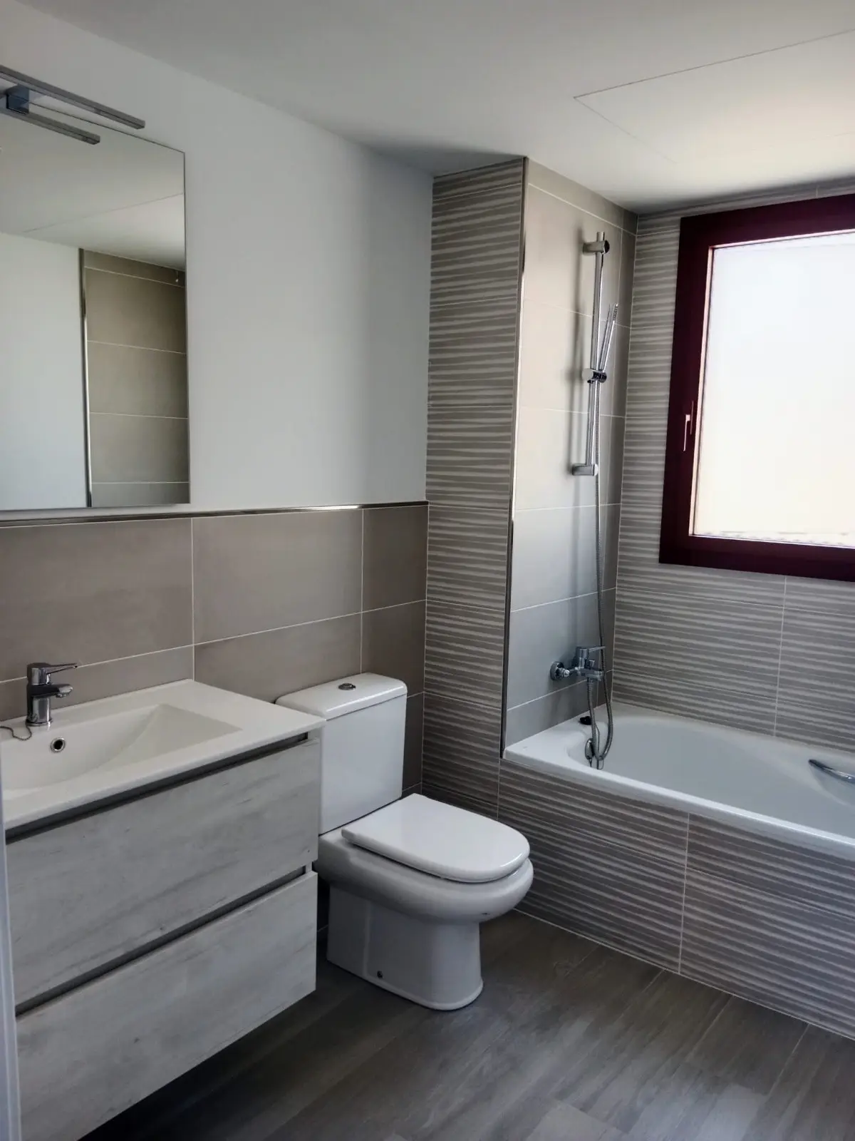 Baño con bañera, azulejo con relieve gris y mueble de lavabo suspendido