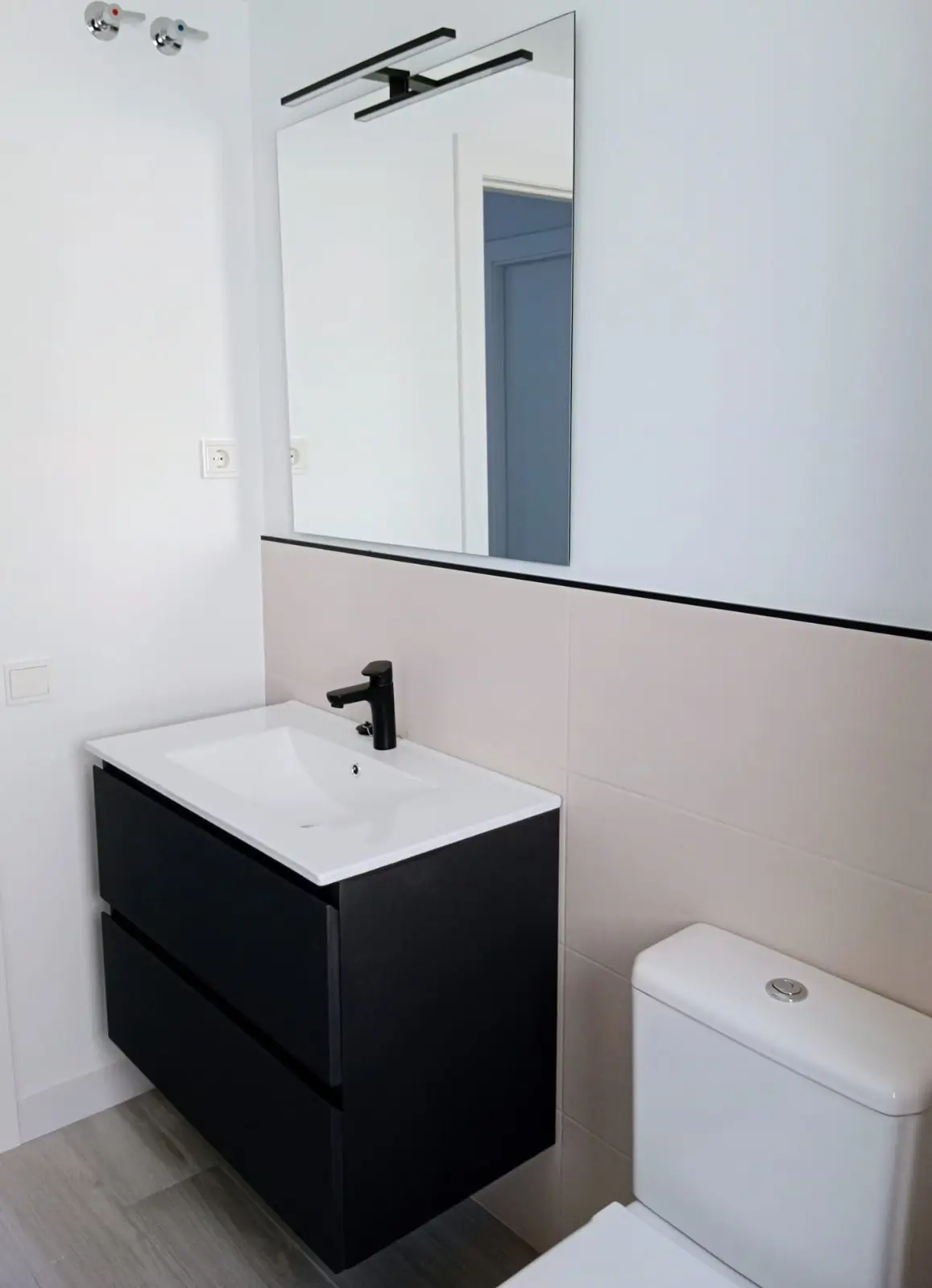 Mueble de lavabo negro con grifería negra y aplacado bicolor