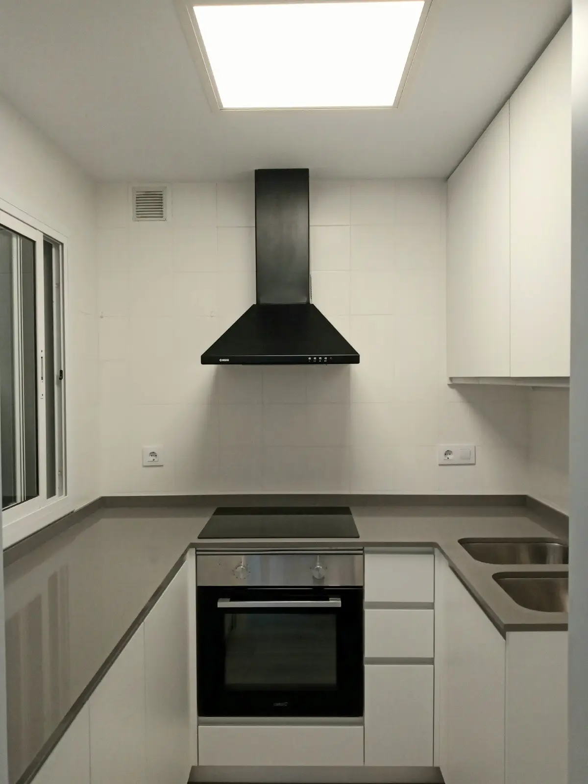 Cocina en U blanca con encimera gris y campana negra