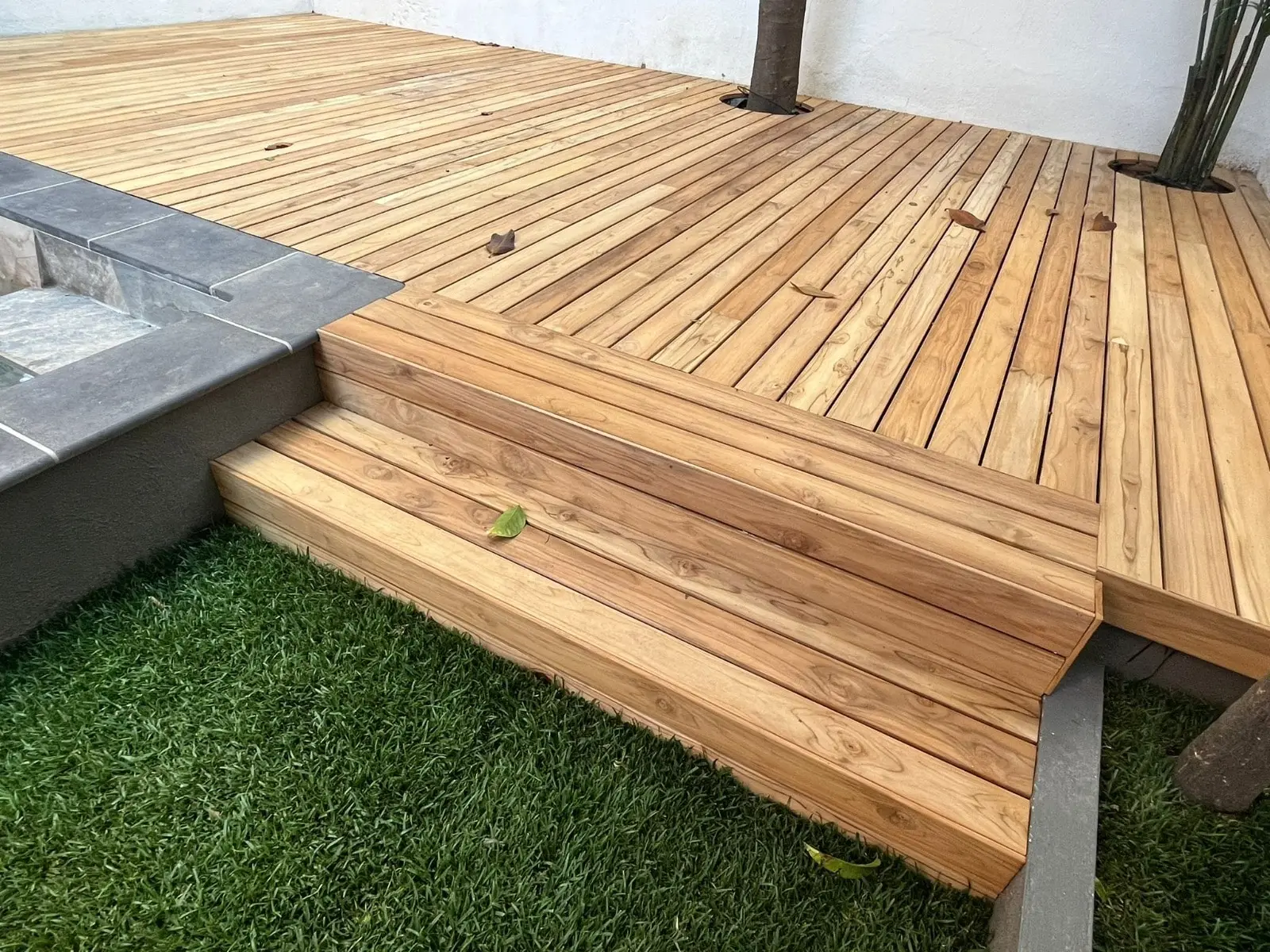 Tarima exterior de madera con escalones junto a piscina