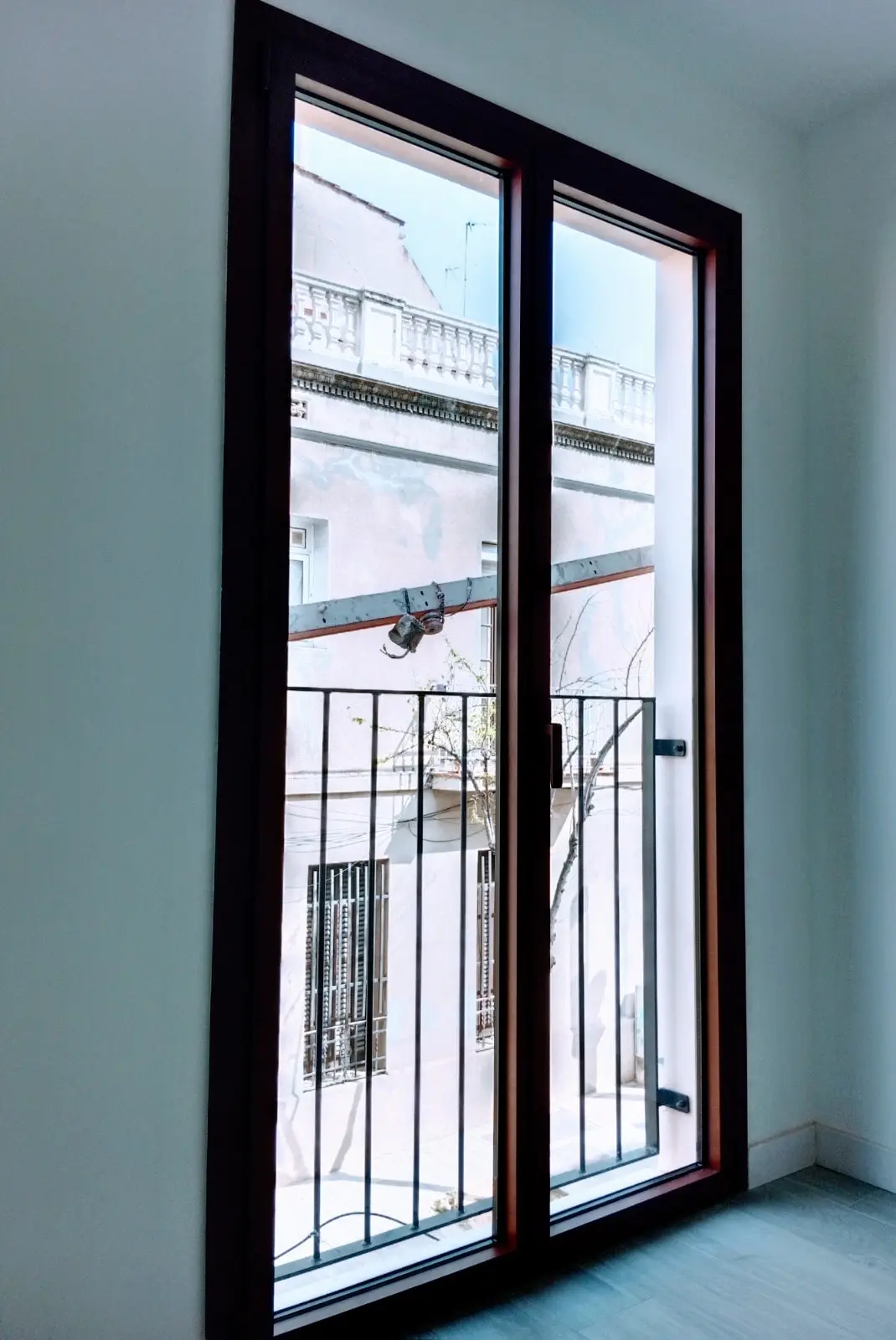 Balconera nueva de madera con doble vidrio en piso de fachada antigua